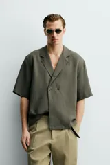 Camisa tipo kimono de corte relaxed fit, color celeste, confeccionada en tejido fluido de viscosa y lino. Presenta cuello con solapas de muesca, manga corta y cierre frontal cruzado con doble botonadura.
