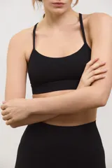 Top deportivo negro de compresión media, con escote redondo clásico, tiras finas cruzadas en la espalda y tazas intercambiables.