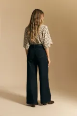 Jean de tiro alto y pierna ancha, confeccionado en denim azul oscuro con costuras a contratono. Presenta un diseño de corte recto y holgado.