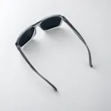 Lentes de sol polarizados con armazón negro de diseño geométrico y detalles metálicos en las patillas.