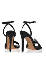 Sandalia de tacón alto color amarillo con pulsera al tobillo y detalle de moño con strass en la capellada.