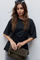 Remera negra de manga corta con cuello redondo y detalle de frunce lateral que crea un efecto drapeado en la cintura. Presenta un corte relajado y versátil.