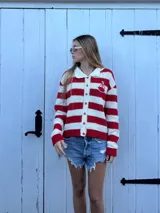 Cardigan tejido a mano en hilo de algodón, en combinación de colores rojo y blanco. Presenta un pequeño bordado de barco en un costado. Su textura es liviana, ideal para los días templados o las noches frescas de verano.