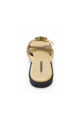 Sandalia plana color beige con punta cuadrada, tiras cruzadas y hebilla metálica dorada decorativa en el empeine.