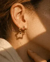 Aros tipo caravana con diseño de estrella formado por múltiples capas de alambre fino en tono dorado.