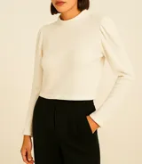 Sweater de lanilla color crudo, con cuello redondo alto, mangas largas con hombros ligeramente abullonados y diseño corto.