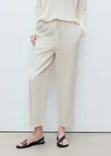 Pantalon de lino color beige, de corte recto y tiro alto. Cuenta con cintura elástica con cordón ajustable y bolsillos laterales.