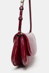Bolso de hombro tipo baguette con acabado brillante, solapa frontal con cierre de botón imantado y asa ajustable.