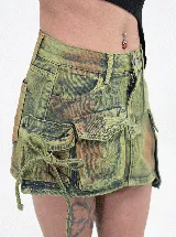 Minifalda de jean con efecto batik en tonos verde y marrón, de corte ajustado. Presenta un diseño tipo cargo con dos bolsillos pequeños superiores y dos bolsillos grandes laterales con solapa.