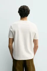 Camiseta de manga corta con cuello panadero y cierre frontal de tres botones. Presenta una textura acanalada y un corte regular fit.