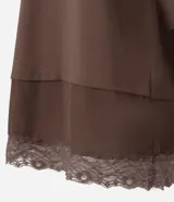 Remera marrón de algodón con cuello redondo, mangas cortas amplias y diseño de superposición con una capa inferior que presenta borde de encaje.