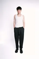 Pantalón de vestir negro, de corte recto, con bolsillos laterales y traseros. Se ajusta a la cintura con cinturón de cuero marrón.