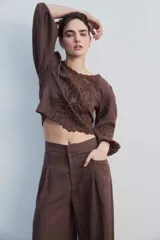 Blusa negra con detalles de apliques bordados en el pecho y las mangas, cuello redondo y mangas largas abullonadas.