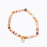 Pulsera elástica compuesta por cuentas planas de piedras naturales en tonos beige, naranja, blanco y marrón, intercaladas con pequeñas cuentas doradas y cuentas más grandes de tonos jaspeados. Incluye un dije redondo metálico dorado.