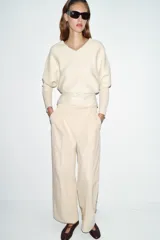 Pantalón de tiro alto con pinzas delanteras, bolsillos frontales y falsos bolsillos de vivo en la espalda. Presenta una pernera recta y cierre frontal con cremallera, botón interior y gancho.