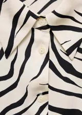 Camisa de poliéster satinado con estampado de cebra, diseño recto y regular fit, manga larga abotonada y cuello camisero.