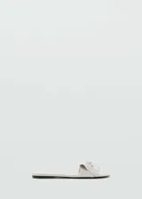 Sandalias planas color blanco off-white, con tira ancha en el empeine decorada con flecos y un pequeño lazo.