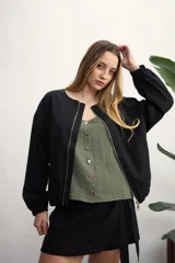 Chaqueta tipo bomber color negro, con cierre frontal metálico, cuello redondo y puños elásticos.