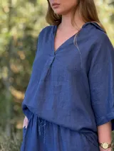 Blusa de lino color blanco, con cuello camisero y escote en V profundo, mangas 3/4 y corte holgado.