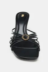 Sandalia de tacón fino y punta cuadrada, color negro, con tiras múltiples en la parte delantera y detalle metálico dorado.