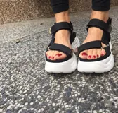 Sandalias negras con plataforma blanca y correas de velcro ajustables.