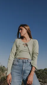 Saco de punto fino color verde menta, con diseño abierto y cierre frontal mediante lazo. Presenta mangas largas y un corte cropped que se ajusta a la cintura.