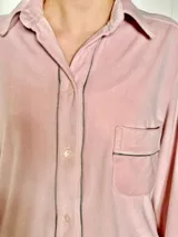 Pijama de dos piezas color rosa pálido, confeccionado en terciopelo. La camisa es de manga larga con botones frontales y bolsillo en el pecho. El pantalón es de corte recto con cintura elástica.