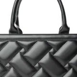 Bolso tote negro de cuero sintético acolchado con diseño rectangular. Tiene doble asa corta y correa larga regulable extraíble. El acceso es con cierre y cuenta con un bolsillo interno con cierre y dos abiertos.