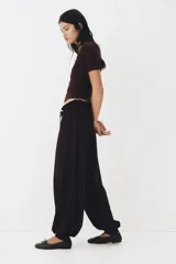 Pantalón globo de corte relajado en punto de crepé, color negro. Cuenta con cintura elástica de tiro bajo con cordón ajustable y piernas globo con puños anchos.