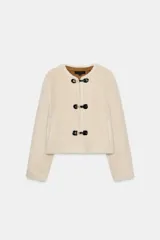 Chaqueta de cuello redondo y manga larga, confeccionada en tejido exterior efecto pelo y forro interior efecto ante. Presenta bolsillos delanteros de vivo y cierre frontal con alamares metálicos y detalles en contraste.