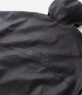 Chaqueta masculina de poliuretano color negro, con diseño de capucha, cierre frontal completo y puños elásticos. Presenta un acabado liso y estructura robusta.