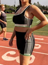 Top deportivo azul con contorno y tirantes blancos, banda inferior blanca con logo en rojo y borde inferior rojo.