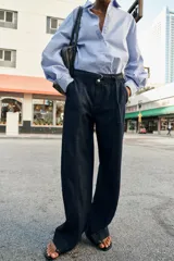 Jeans de tiro alto con corte bootcut, confeccionados en denim azul oscuro. Presentan costuras verticales decorativas en el frente, bolsillos laterales y cinturón del mismo tejido con hebilla metálica.