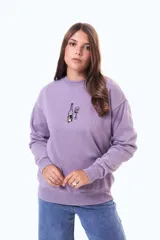 Buzo de felpa oversize color violeta con cuello redondo y estampa frontal pequeña de una botella y una copa de vino.