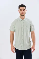 Camisa de manga corta confeccionada en mezcla de lino y algodón, color beige, con cuello camisero abotonado, bolsillo frontal en el pecho y cierre de botones.