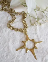 Collar de cadena gruesa con eslabones circulares color bronce, con dije en forma de sol con puntas.