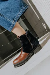 Botas de cuero marrón con la caña recubierta de corderito verde. Presentan una suela de plataforma tipo track en color beige y un tirador en la parte posterior para facilitar el calce.