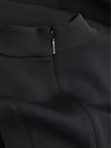 Vestido midi negro de punto técnico con corte entallado, cuello perkins, cremallera trasera, sin mangas, recortes en forma de media luna en los hombros, detalles de costuras verticales en la parte frontal y posterior, y hendidura en la espalda.