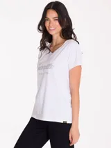 Remera de cuello en V, manga corta, color blanco con estampa metálica frontal de la marca Caterpillar.