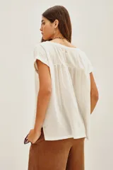 Remera de manga corta color blanco roto, con escote bote y calce holgado.