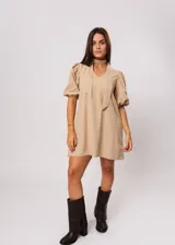 Vestido corto color beige, de corte oversize, con escote en V y mangas globo. Incluye cinturón marrón con hebilla dorada.