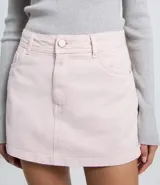 Short pollera de sarga color beige, con diseño de tiro medio, trabillas en la cintura, bolsillos laterales y cierre frontal con botón y cremallera.