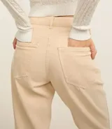 Pantalón mom de sarga color beige, con cintura alta, trabillas, bolsillos delanteros y traseros, cierre con botón y cremallera.