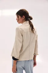 Chaqueta de lino lavado color blanco, con cuello mao, cierre metálico diagonal y detalles en contratono.