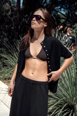 Pantalón de tiro medio con cintura elástica y pierna ancha. Presenta bolsillos laterales ocultos en la costura y un diseño fluido.