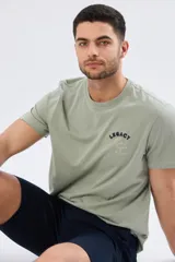 Remera de algodón color verde militar, con cuello redondo y mangas cortas. Presenta un pequeño estampado y bordado en el pecho con la inscripción "Legacy".