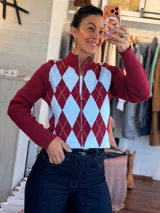 Campera de punto con diseño de rombos en colores bordó y celeste, con cuello alto y cierre frontal completo. Posee mangas largas con puños acanalados.