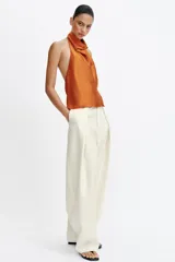 Top de cuello halter satinado en color naranja tostado, con espalda descubierta y cierre trasero de botones.
