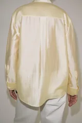 Camisa de mujer fluida de ZARA WOMAN COLLECTION, confeccionada en hilatura con mezcla de lyocell. Presenta escote en pico, manga larga con puños marcados y bajo asimétrico, con cierre frontal de botones ocultos.