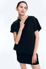 Remera negra de algodón, corte amplio, con cuello redondo y mangas cortas.